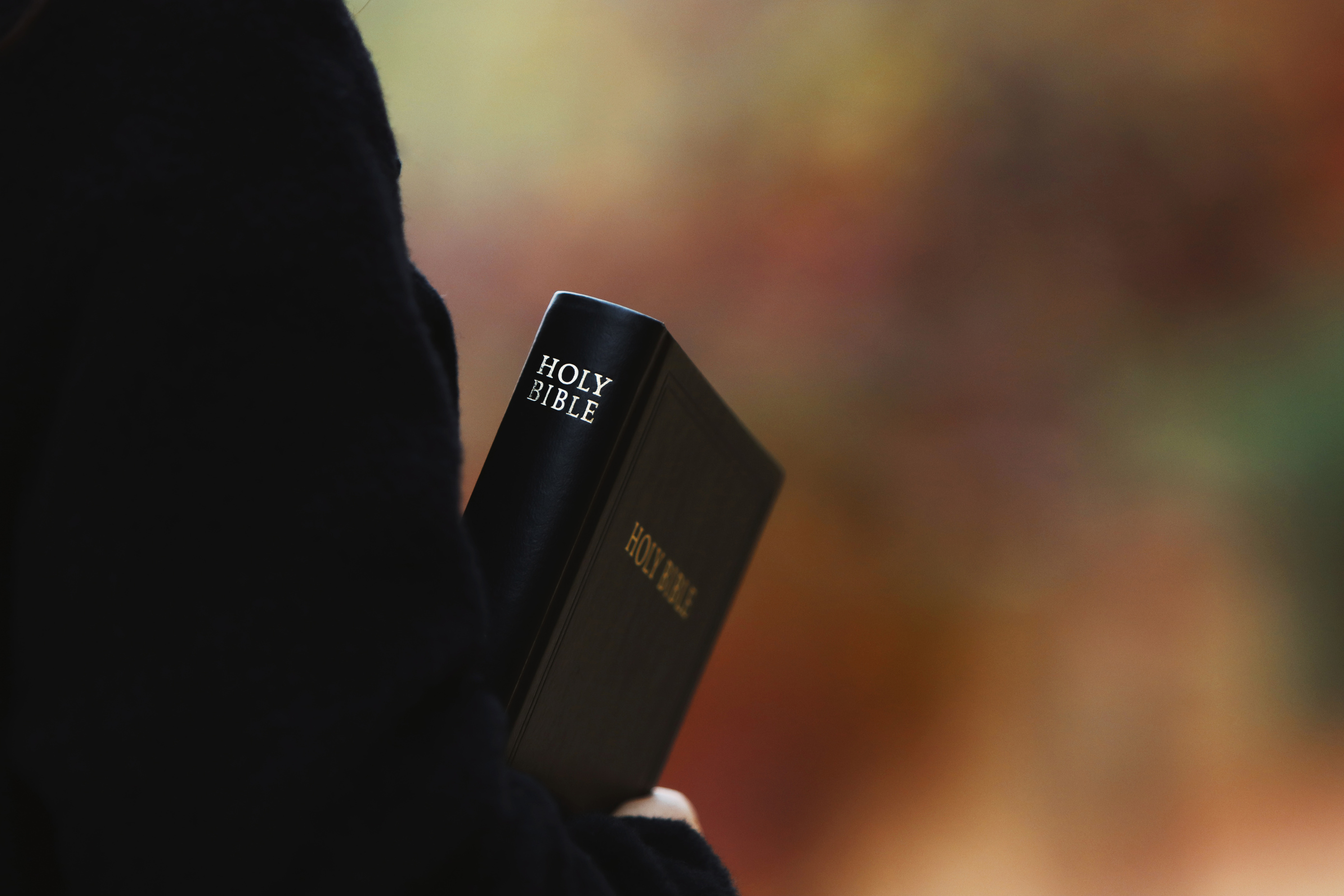 Christian preaching the gospel with holy bible on autumn street